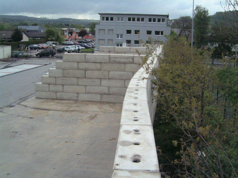Abgestufte Betonblocksteinwand neben einer gekrümmten Reihe mit anderem Steinformat